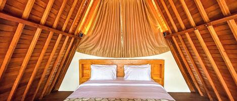 A bedroom with a wooden ceiling, a bed with white bedding, and a patterned throw.