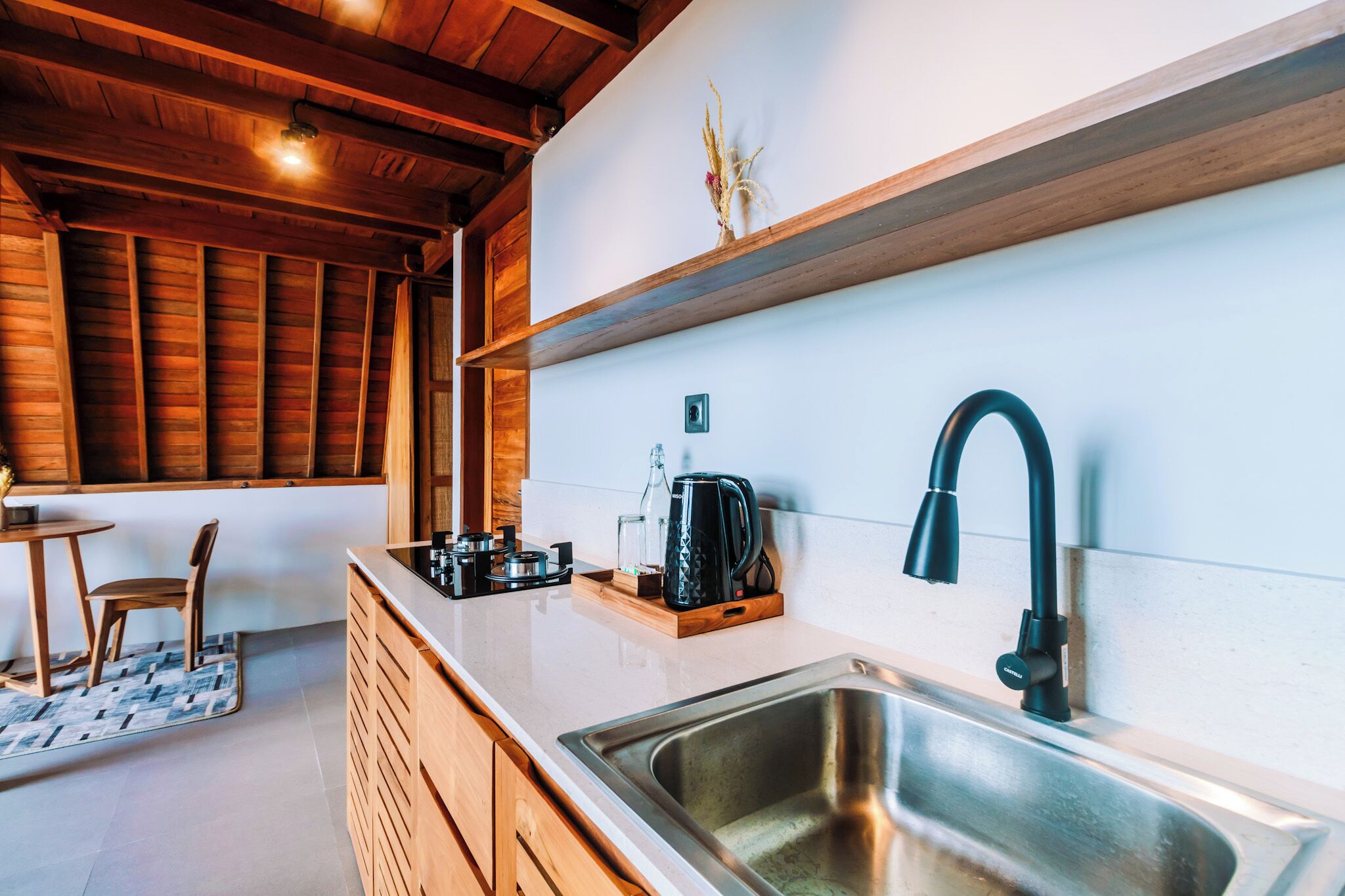 Una cocina moderna con armarios de madera, un lavamanos de acero inoxidable, un grifo negro y una cafetera en la encimera.