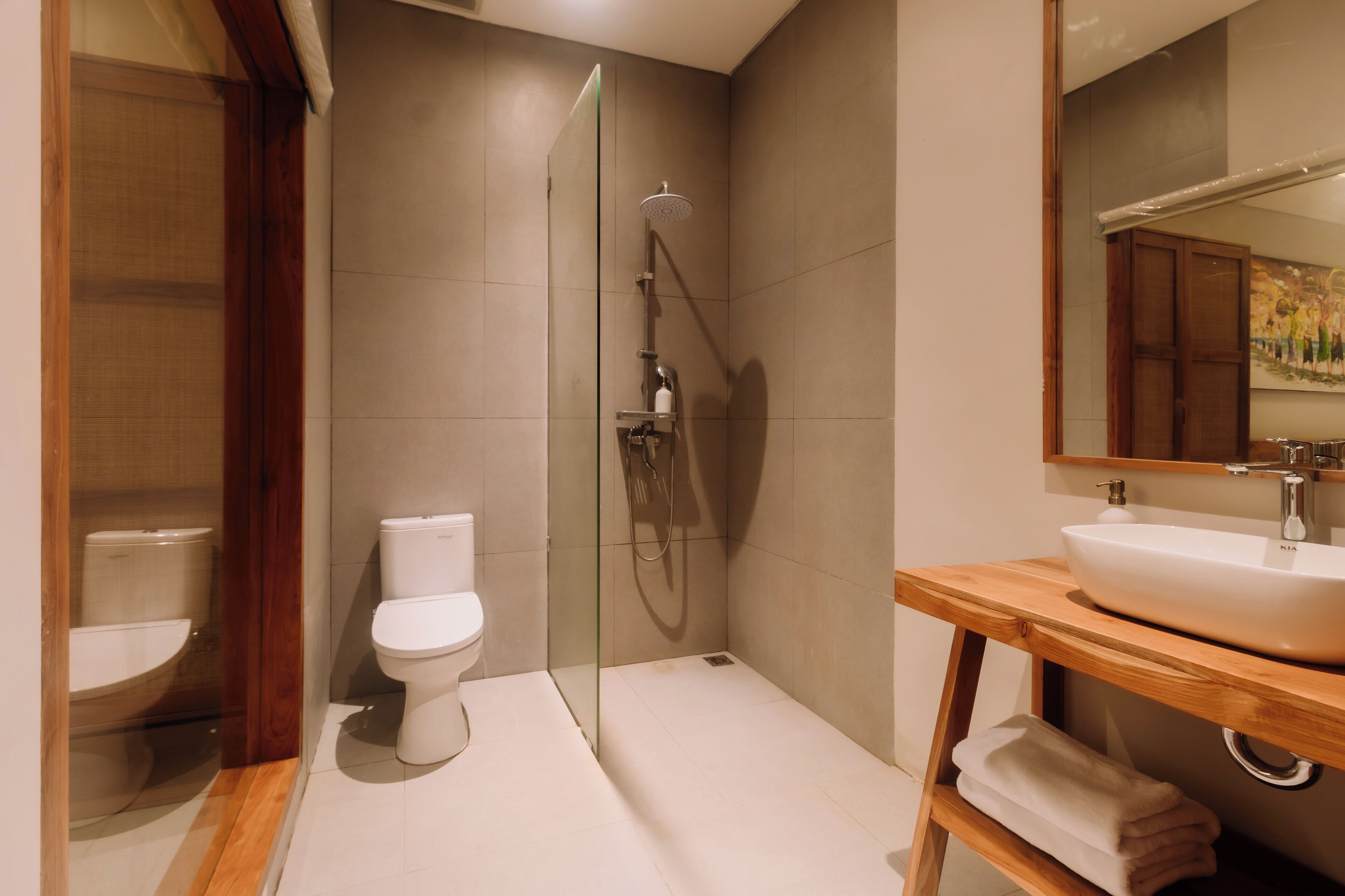 A modern bathroom with a glass-enclosed shower, a wooden vanity with a sink, and a toilet.