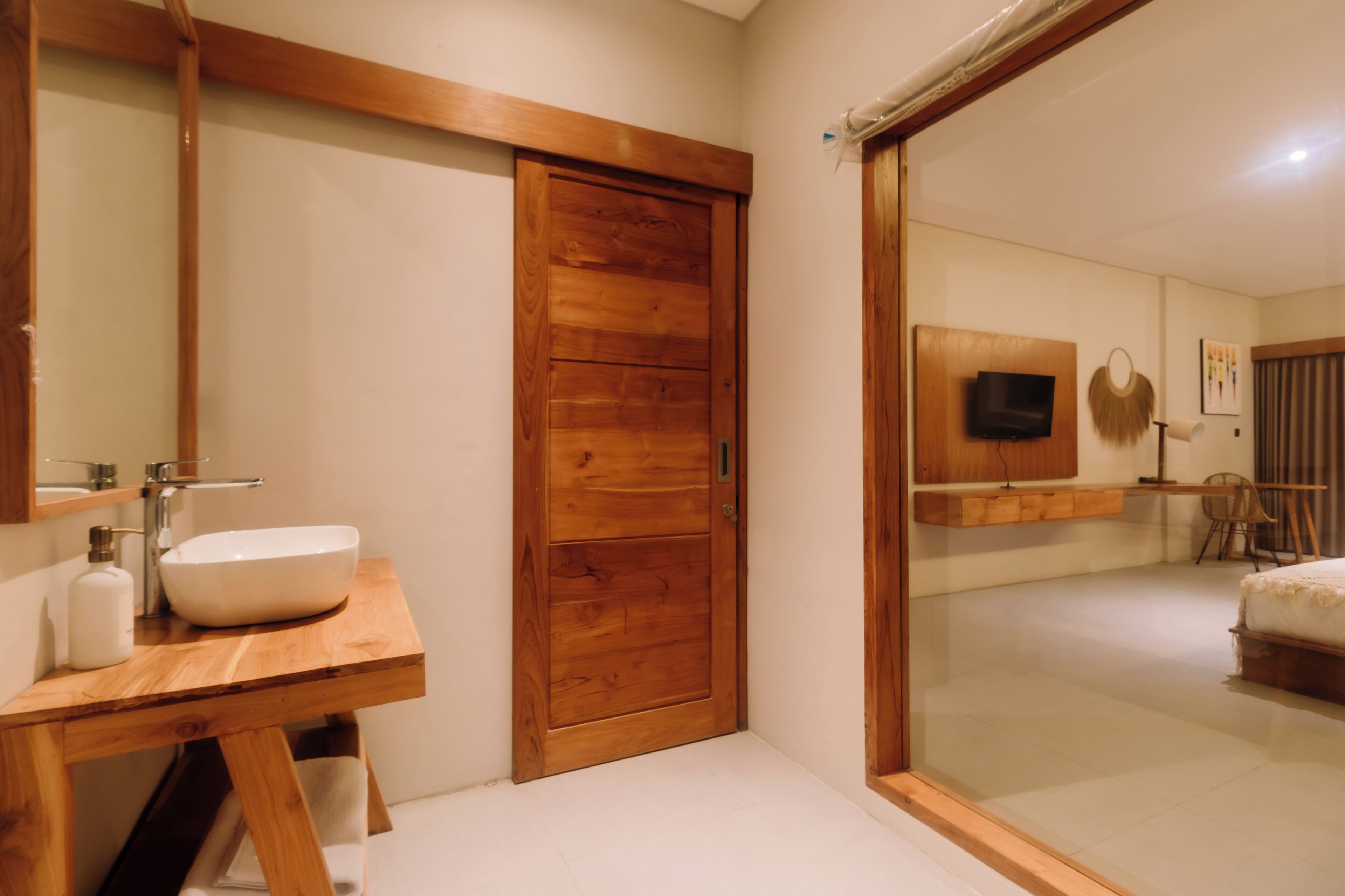 A modern bathroom with a wooden vanity, a large mirror, and a built-in sink.