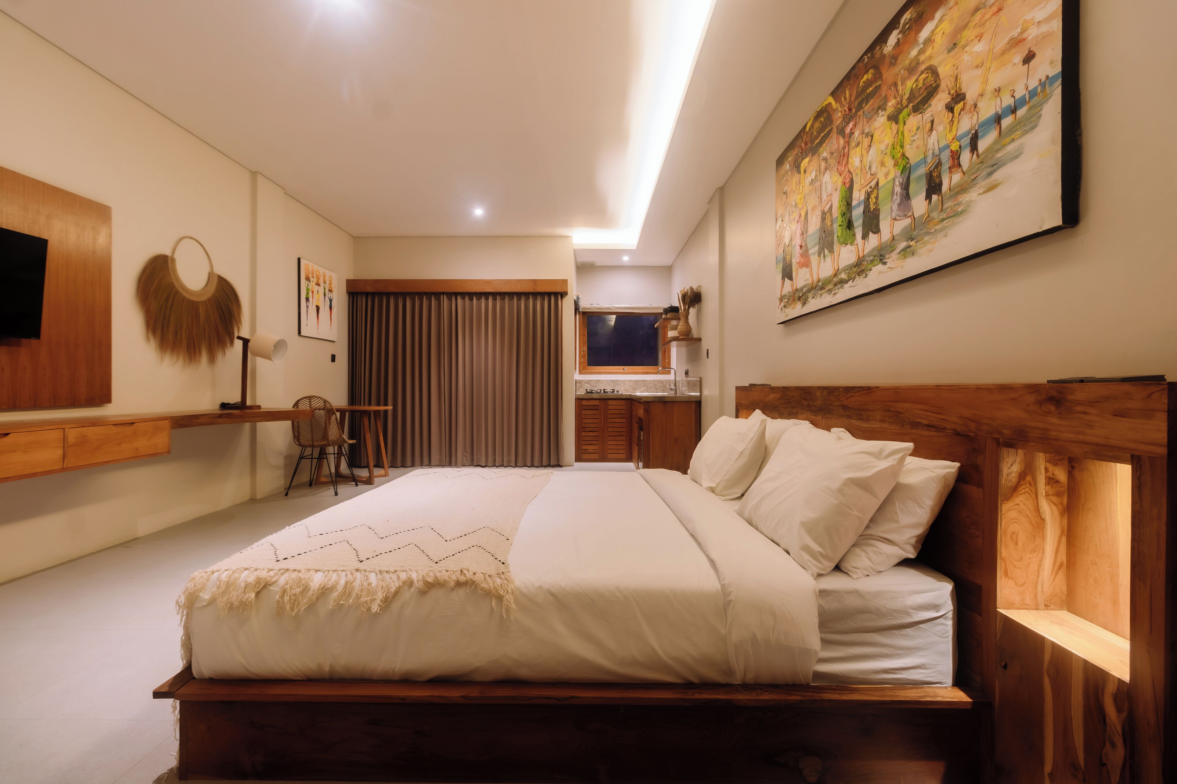A bedroom with a large bed, a desk, a chair, a TV, and a painting on the wall.