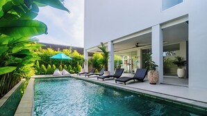 A modern pool area with lounge chairs and a covered seating area. - Campbar 4 (Munggu)