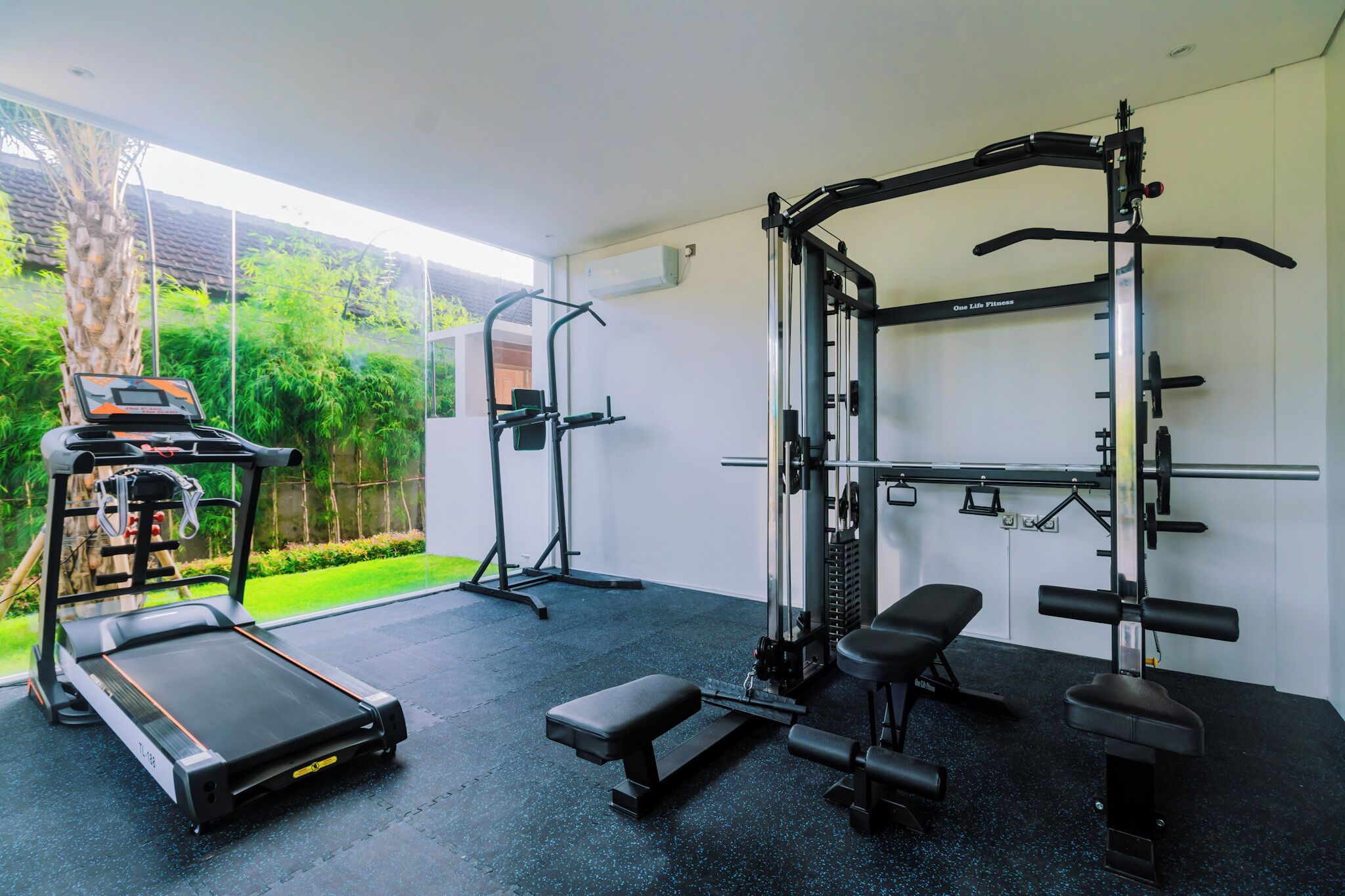 Ein Heimfitnessraum mit Laufband, Bankpresse und Gewichtsheberbank.