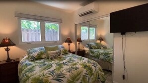 Een slaapkamer met een bed, twee bedlampen, een grote spiegel en een tv die aan de muur is bevestigd.