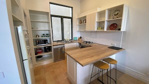 A modern kitchen with a wooden countertop, a dishwasher, a microwave, and a sink. There are two stools and a window with a view of the outside. - 2 bed apartment for up to 6 people in awesome beachside Hampton (Hampton)