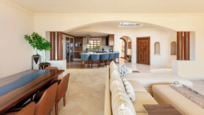 A spacious living area with a dining table, a sofa, and a kitchen in the background.