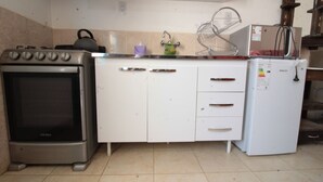 A kitchen with a stainless steel stove, white cabinets, and a white refrigerator. - Monoambiente Centrico en Tilcara (Tilcara)