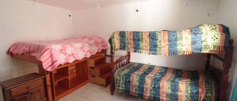 Una habitación pequeña y acogedora con dos literas, un aparador de madera y una mesita.