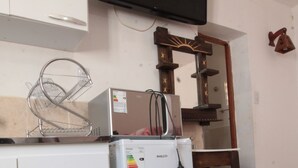 A kitchenette with a white refrigerator, a microwave, and a small sink. A flat-screen TV is mounted on the wall above the counter. - Monoambiente Centrico en Tilcara (Tilcara)