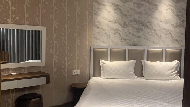 Une chambre d’hôtel moderne avec un grand lit, une coiffeuse avec un miroir et une petite table ronde.