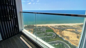 Ein Balkon mit Blick auf eine Küstenlandschaft, darunter ein Strand und kurvenreiche Straßen.