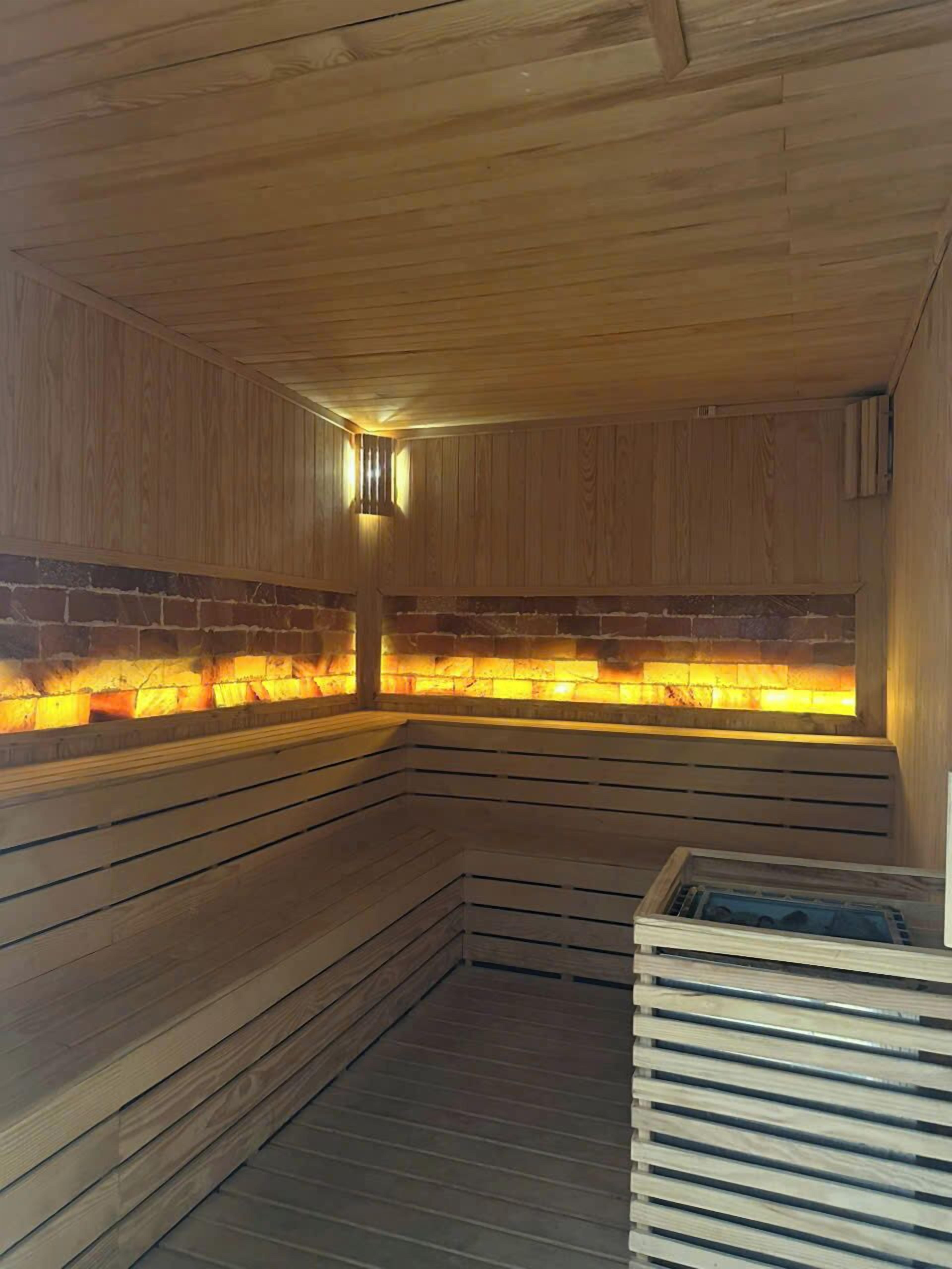 Una sauna con bancos de madera y pared de ladrillo.