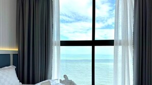 Ein Hotelzimmer mit großem Fenster und Blick auf das Meer.