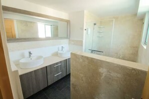 Une salle de bain moderne avec deux lavabos, un grand miroir et un espace douche.