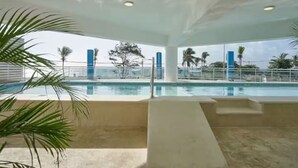 A pool area with a view of palm trees and a distant shoreline.