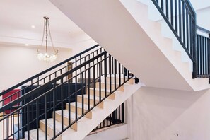 Una escalera con barandillas negras y escalones blancos que conduce a un piso superior.