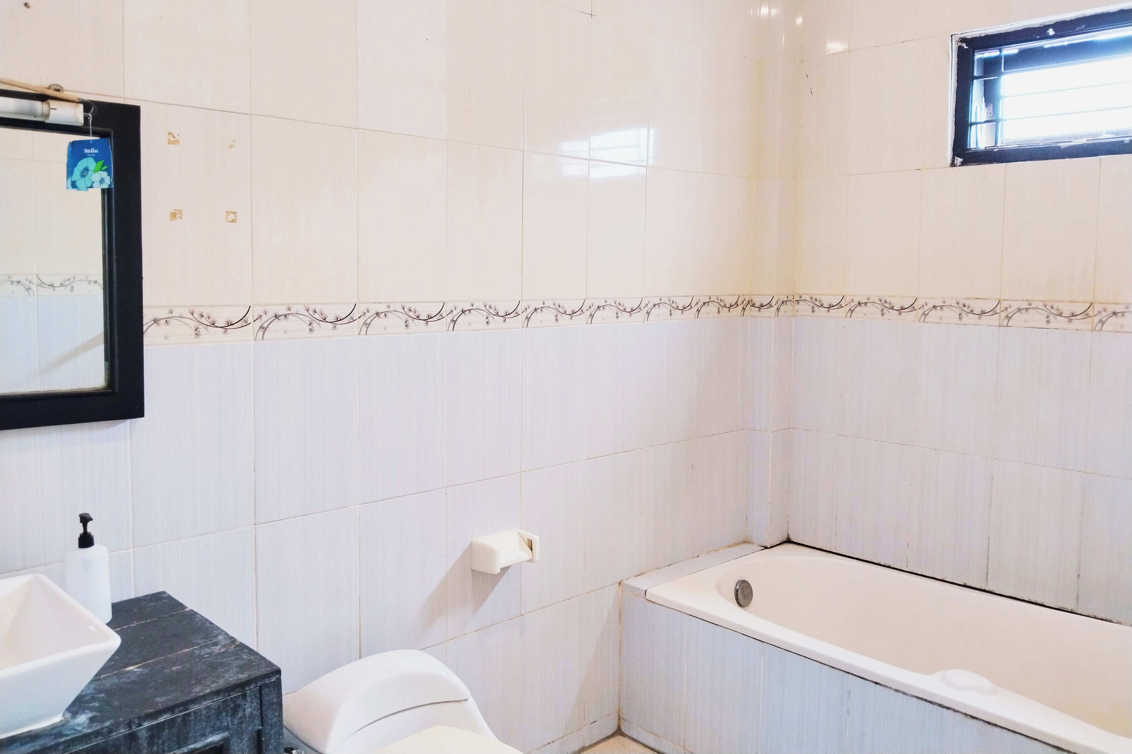 A bathroom with white tiles, a black sink, a toilet, and a bathtub.