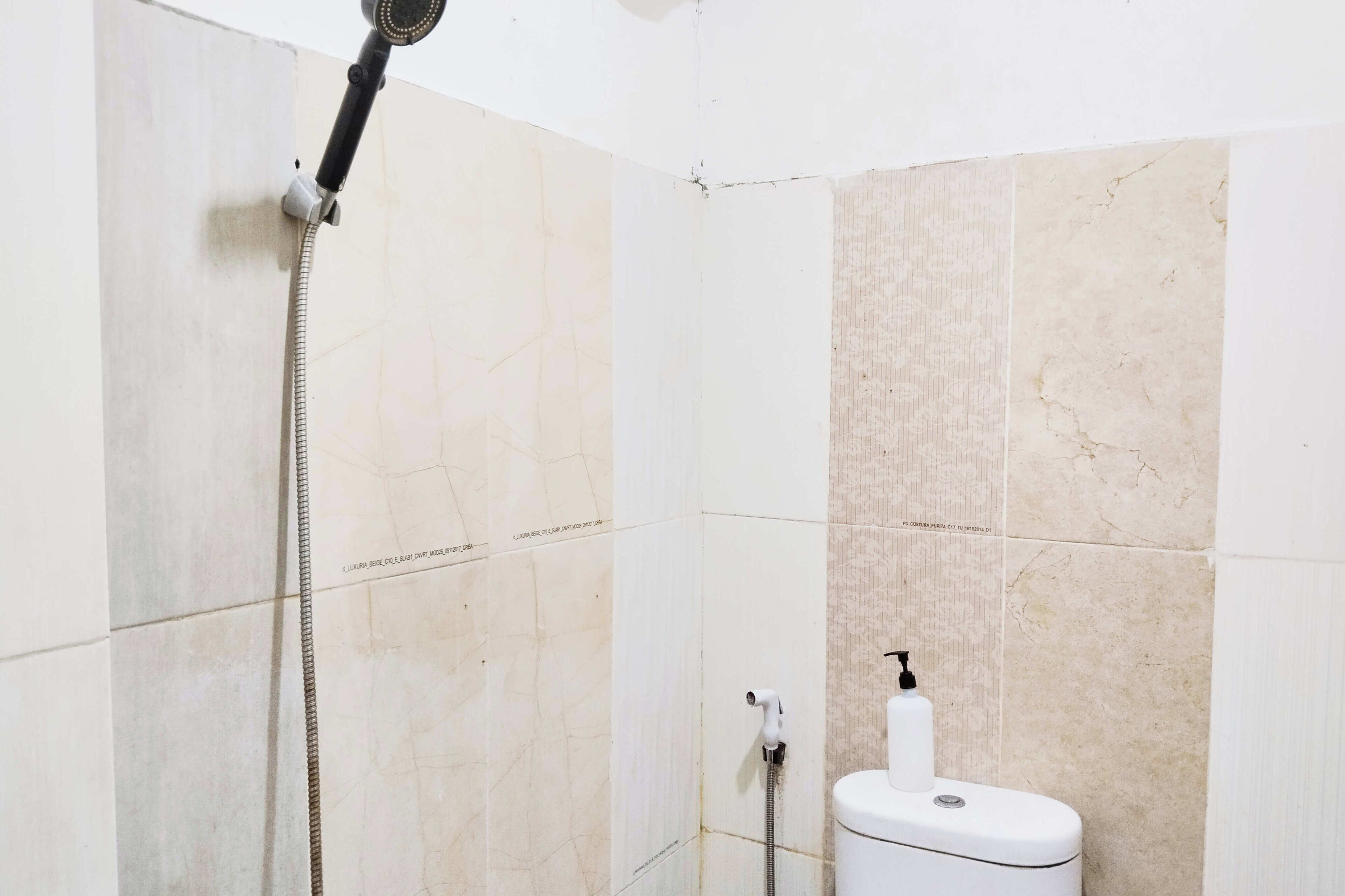Een badkamer met een douche, toilet en een handdoekdispenser.