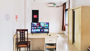 Una habitación con escritorio, silla, televisión y armario.