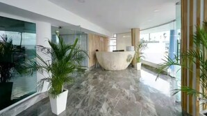 A modern reception area with a curved reception desk, glass walls, and potted plants.