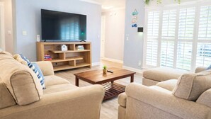 A living room with a flat-screen TV, a wooden entertainment unit, and a sliding glass door to the outside.