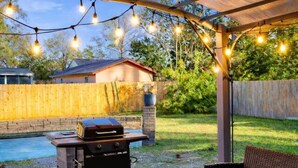 An outdoor patio with wicker furniture, a grill, and string lights.