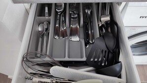Un tiroir contenant divers ustensiles de cuisine, notamment des cuillères, des fourchettes, des couteaux et une spatule.