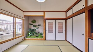 A traditional Japanese room with tatami flooring, sliding doors, and a view of the outside. - Fuji Holiday (Fujiyoshida)