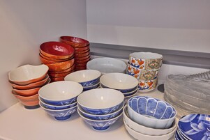 A variety of bowls and plates stacked on a shelf.