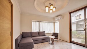A modern living room with a sectional sofa, a round coffee table, and a view through a sliding glass door. - Fuji Holiday (Fujiyoshida)