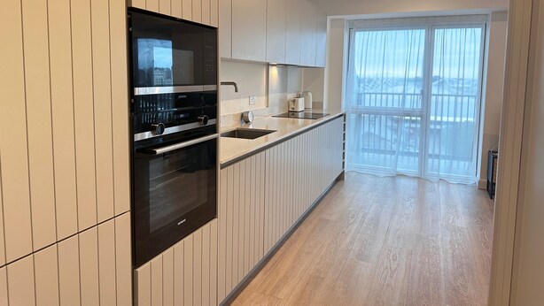 A modern kitchen with white cabinetry, a built-in oven, and a microwave. - Excel London Gateway Apartments (London)