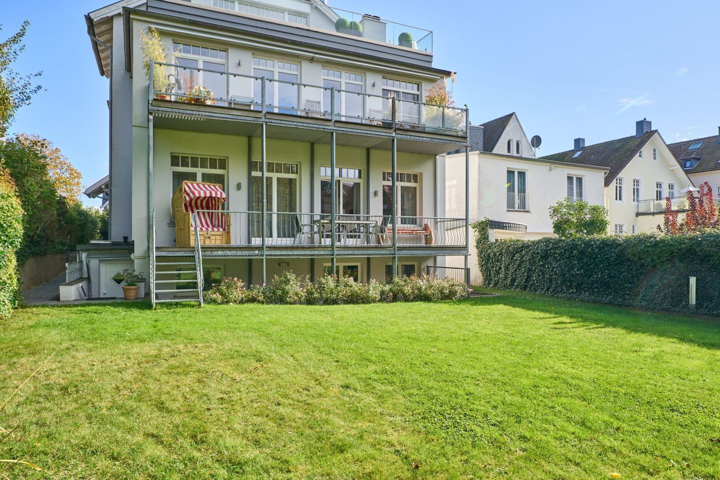 Une maison à deux étages avec un balcon et un petit jardin.