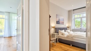 Un dormitorio con una cama grande, una mesita de noche, una lámpara y una ventana con vistas a zonas verdes.
