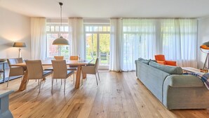 Una sala moderna con una mesa de comedor de madera, sillas, un sofá y una lámpara.