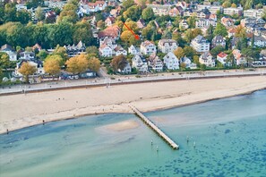 Une zone résidentielle côtière comprenant des maisons, une plage et une jetée qui s’avance dans l’eau.