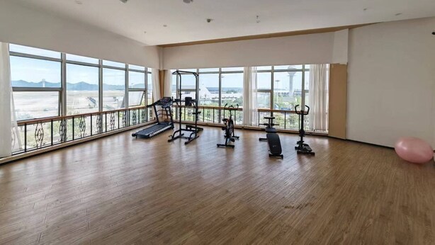 A spacious gym with large windows, exercise equipment, and a wooden floor. - Holiday Inn Chongqing Yungang (Chongqing)