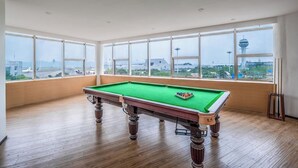 A pool table in a room with large windows offering a view of a cityscape. - Holiday Inn Chongqing Yungang (Chongqing)