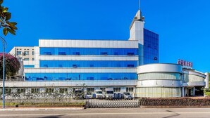 A modern building with a prominent tower and a curved section with signage. - Holiday Inn Chongqing Yungang (Chongqing)