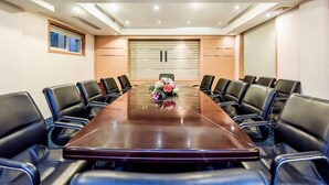 A conference room with a long table, black leather chairs, a floral centerpiece, and a large window with blinds. - Holiday Inn Chongqing Yungang (Chongqing)