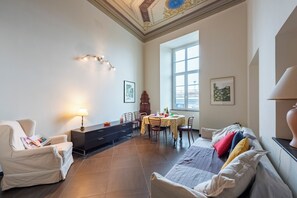 Ein Wohnzimmer mit einer Couch, einem Esstisch und einer Lampe.