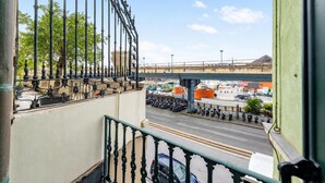 Un balcon donnant sur une rue, un pont et des véhicules garés.