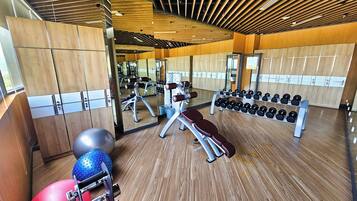 A gym with wooden floors, exercise equipment, and lockers.