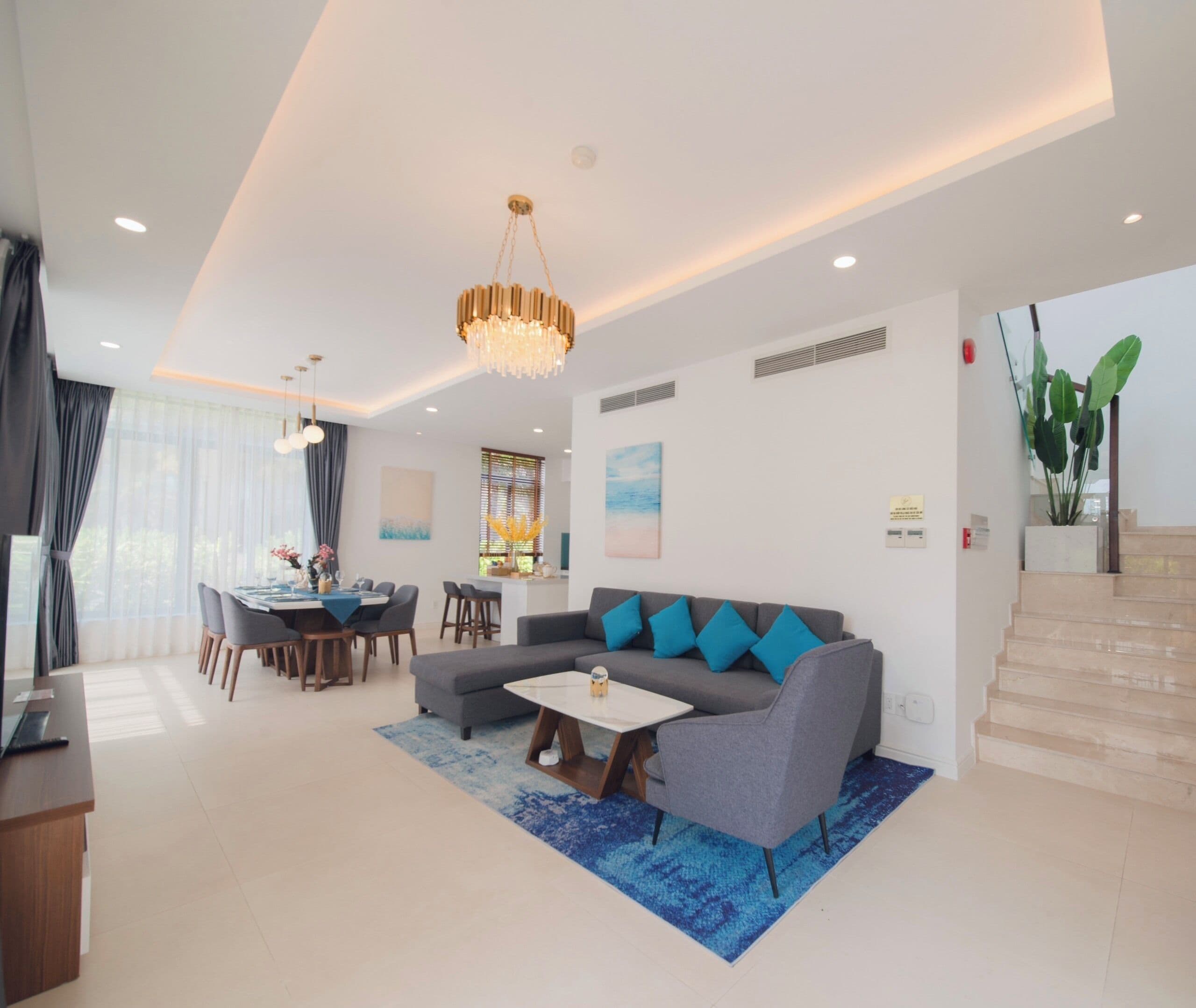 A modern living room with a grey sofa, a coffee table, and a dining area with a table and chairs.