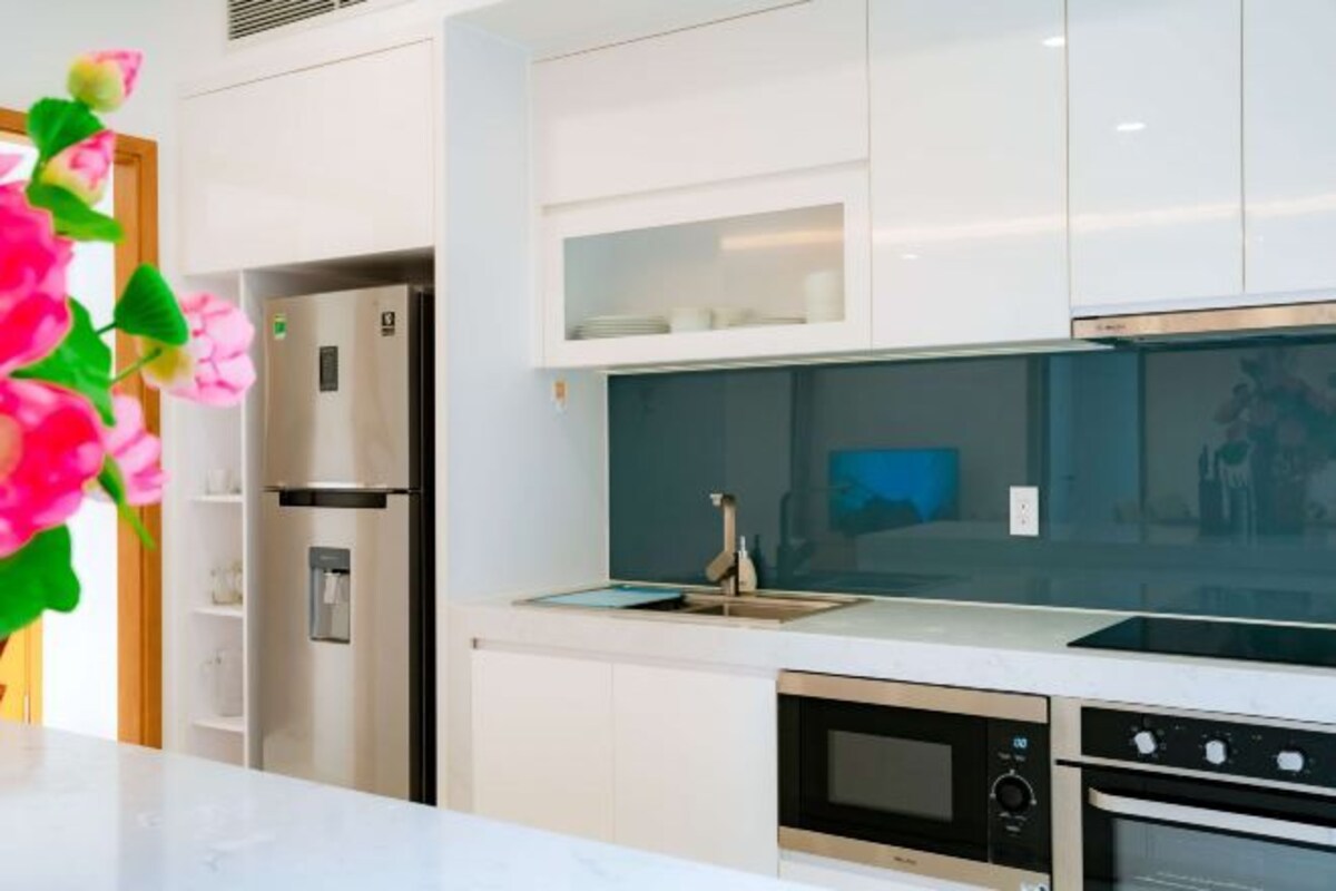 A modern kitchen with white cabinetry, a built-in oven, and a stainless steel range hood.