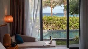 A bedroom with a large window overlooking a pool and ocean, a bed with a laptop, and a lamp on a nightstand. - Hese Pool Villas & Resort Cam Ranh (Cam Lam)