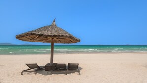 A beach umbrella with a woven design, a wooden post, and four lounge chairs. - Hese Pool Villas & Resort Cam Ranh (Cam Lam)