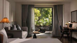 Una camera d'albergo moderna con un letto, una scrivania, un portatile e un'area pranzo con tavolo e sedie.