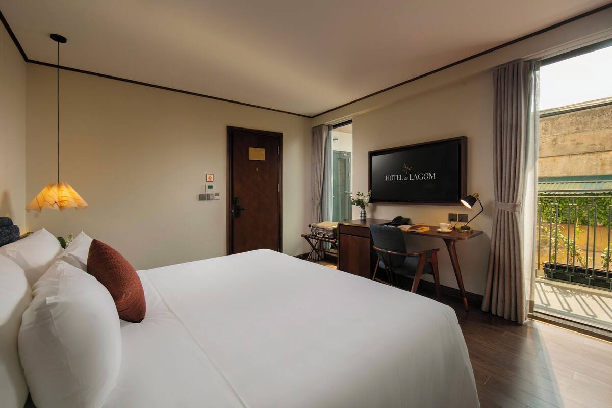 Een hotelkamer met een groot bed, een bureau, een televisie en een balkon met uitzicht.