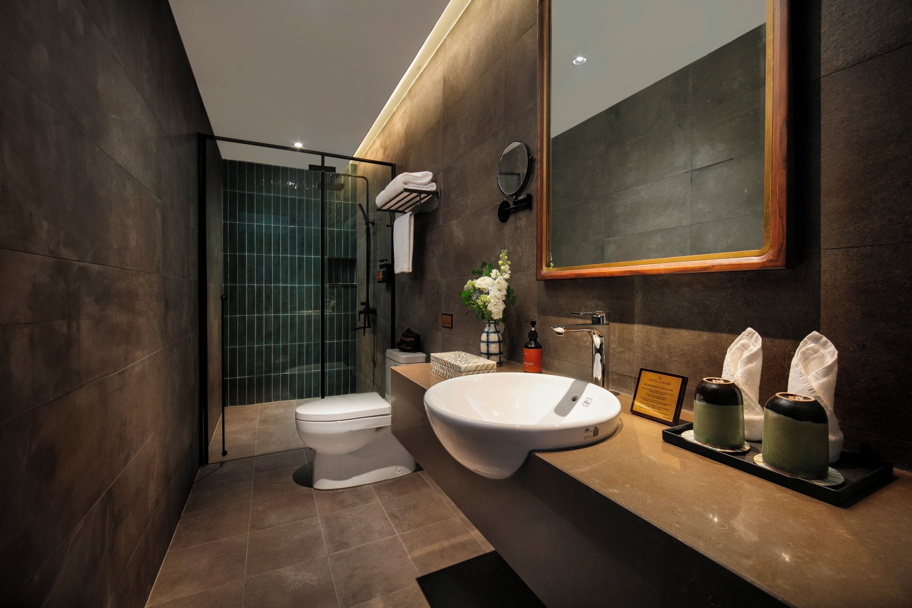 A modern bathroom with a large sink, a toilet, a shower, and a mirror.