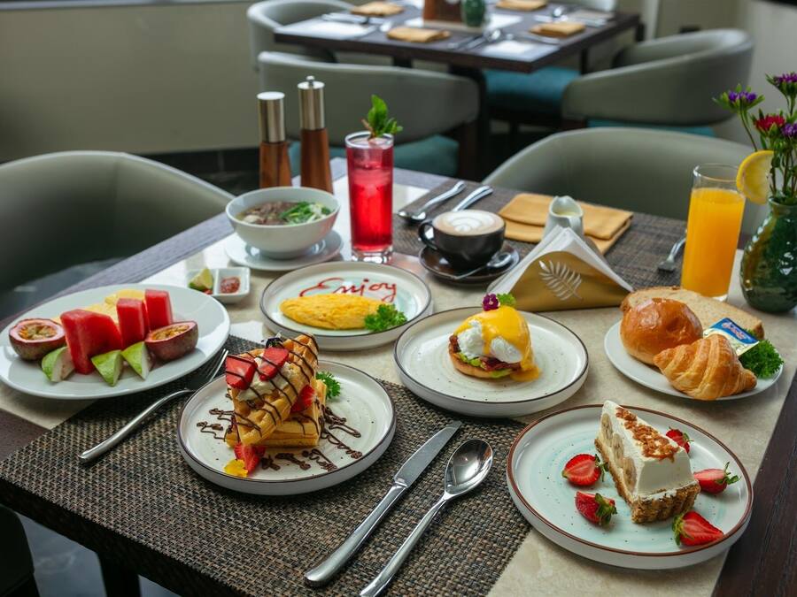 Una colazione con diversi piatti, tra cui waffle, uova, croissant e frutta.
